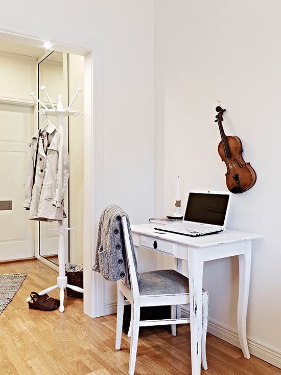 Drewniany biały wieszak i małe biurko w aranżacji małego mieszkania