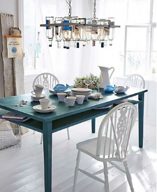 Żyrandol vintaghe z metalu i butelek nad niebieskim stołem z drewna i białymi rustykalnymi krzesłami