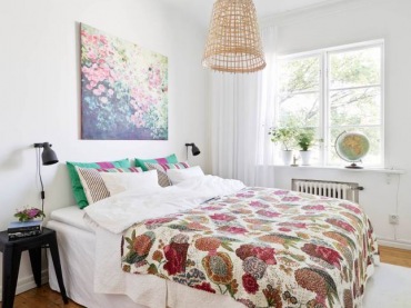 Pleciony abażur wiszącej lampy,narzuta i obraz z motywem kolorowych kwiatów,turkusowo różowe poduszki w sypialni (24921)