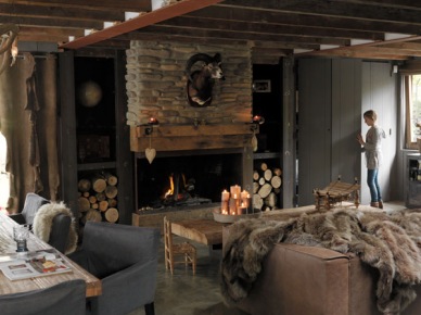 Drewno i naturalny kamień przy kominku w rustykalnym salonie ze skórzaną sofą,futrzakami i betonową podłogą (27676)