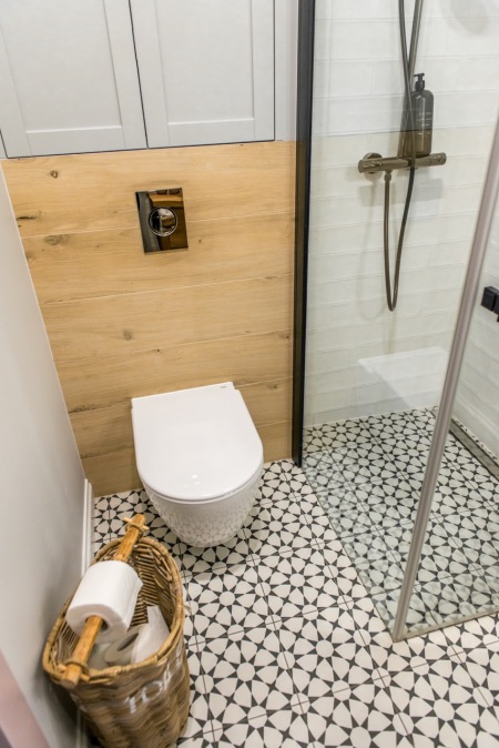 Drewniana zabudowa i wzorzysta podłoga w malutkiej łazience