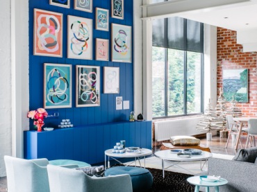 Niebieska ściana, niebieska komoda i błękitne fotele na biało-czarnym dywanie. Cudowne wnętrze, odważne, pełne energii...
