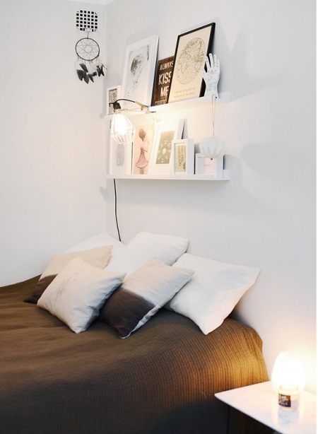 Biała sypialnia z półkami na bibeloty nad łóżkiem