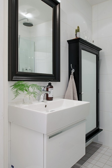 Prostokatne czarne lustro i szafki lustrzane w aranżacji białej łazienki