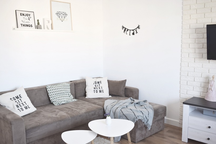 Szara sofa i drobne dekoracje typografią w salonie