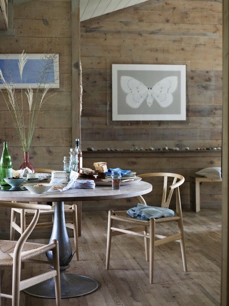 Artprinty z motylem,szaro-beżowe deski na ścianach,skandynawskie giete krzesła z drewna i okrągły stolik na stylowej metalicznej nodze z drewnianym blatem