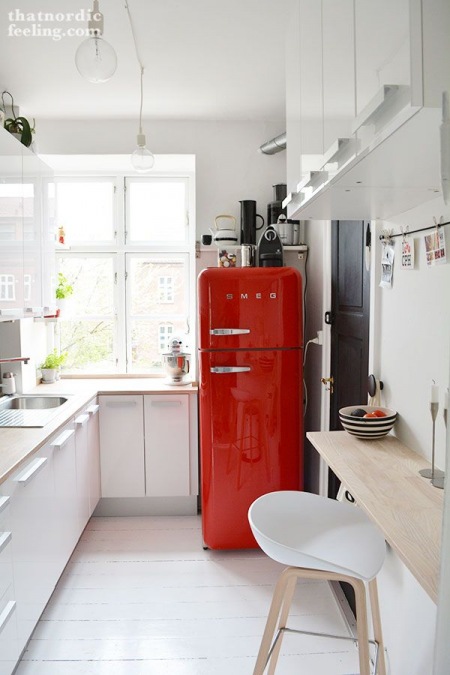 Czerwona lodówka SMEG w wąskiej białej kuchni