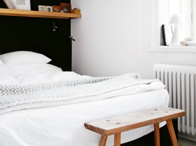 Czarna ściana z łóżkiem i drewniana połka w białej sypialni (20754)