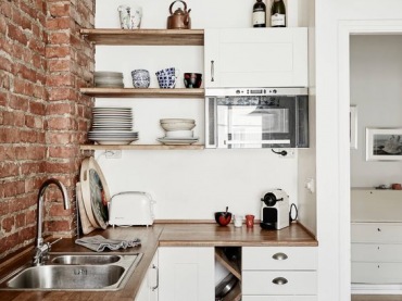 W małej kuchni czerwone cegły zajmują sporo miejsca na ścianie. Brak wiszących szafek czy półek sprawia, że cegły mogą...