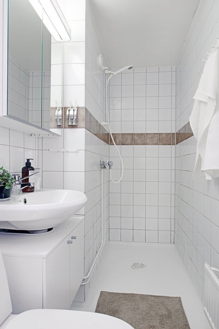 Biała łazienka z brązowym dekoracyjnym paskiem na scianie