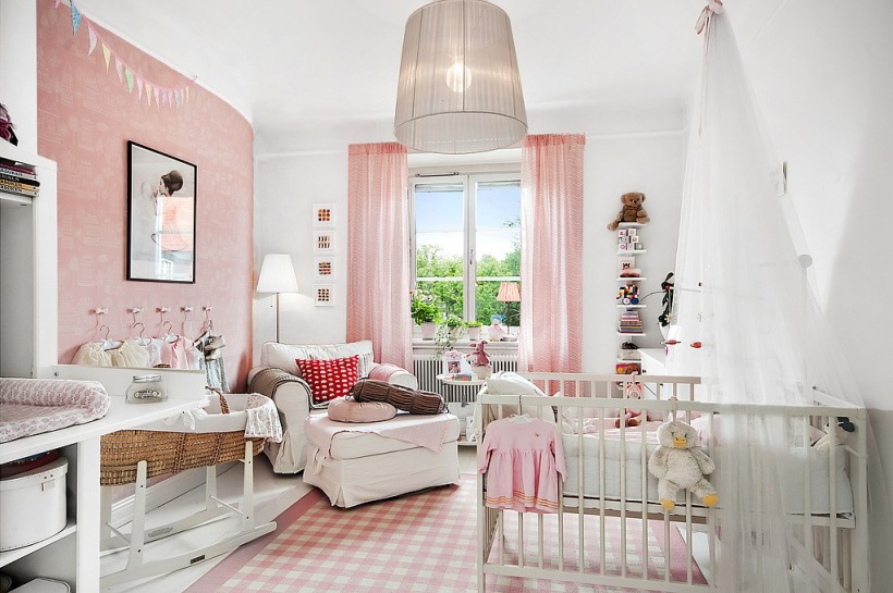 Różowa tapeta ścienna,biało-różowy dywanik w kratkę,różowe lekkie zasłony i białe meble w pokoju dziecięcym