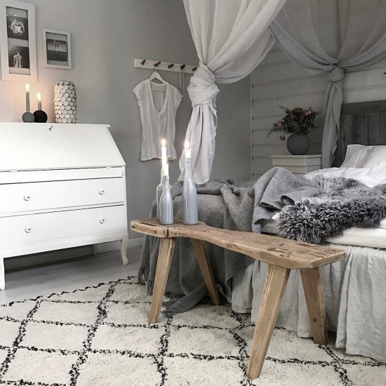Szara sypialnia ze wzorzystym dywanem i drewnianą ławką