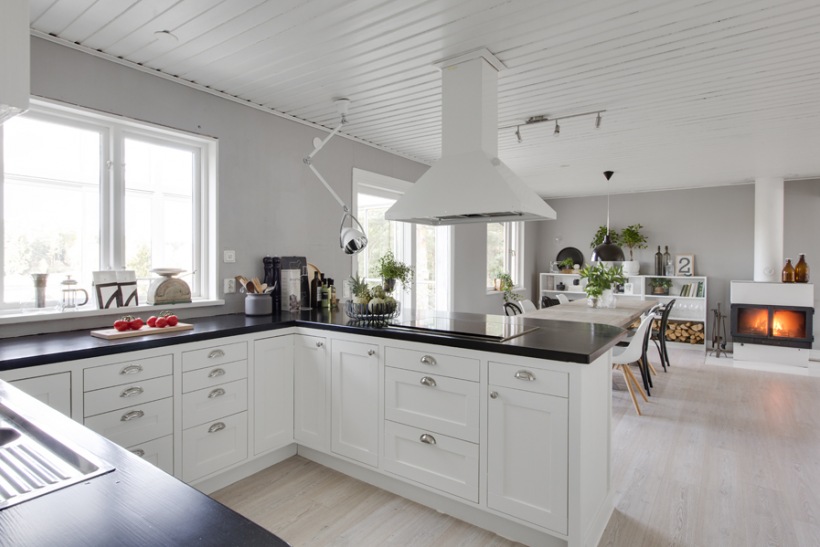 Biały okap nad czarną ladą kuchenną w otwartej na salon kuchni skandynawskiej