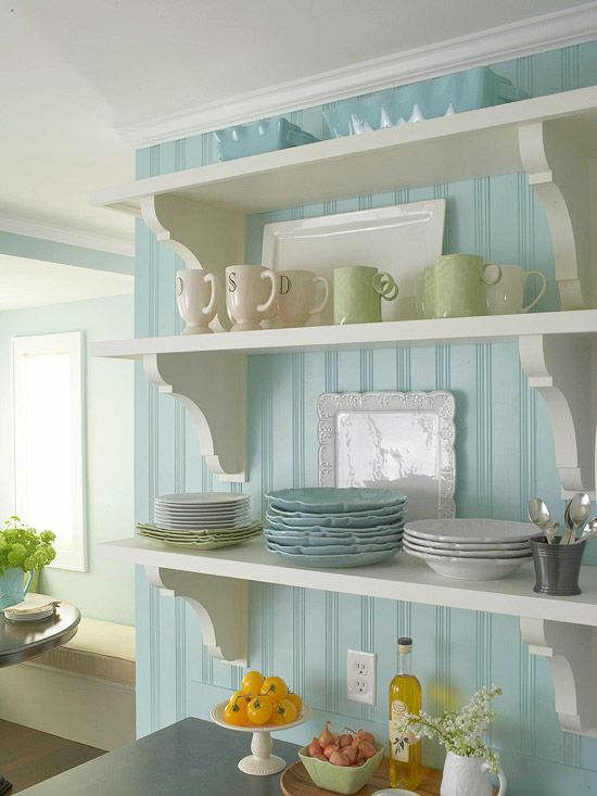 Białe ;półki na niebieskiej tapecie na scianie w kuchni
