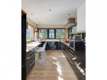 Wystrój kuchni jest dość elegancki i nowoczesny. W aranżacji znajdują się drewniane elementy, w tym podłoga, blaty, a nawet ramy okienne. Idealnie podkreślają klimat całego...