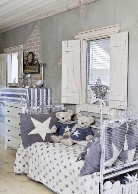 Kute łóżeczko w biało-niebieskiej dekoracji i drewniane okiennice w pokoju dziecięcym