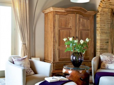 ciepły i swojski klimat w salonie, to drewniane belki, duży, tradycyjny kominek i meble z drewna oraz skórzane sofy - to przykład klasycznego wnętrza we włoskim, wiejskim...