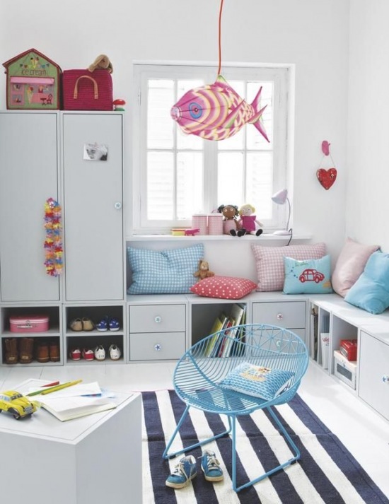 Szafki niskie w roli siedziska dla dzieci,niebieski fotelik z metalu i różowo-niebieskie dekoracje i poduszki