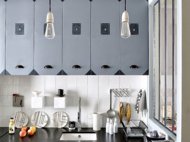Żarówki na kablu,szare szafki z metalowymi okuciami i czarne blaty w małej kuchni (23668)