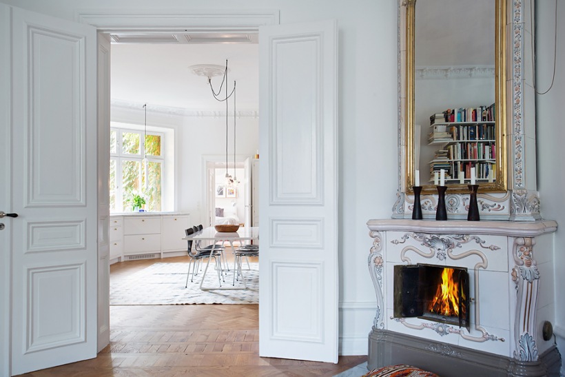 Białe, stylowe drzwi i kominek w salonie