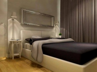 Sypialnia wygląda bardzo stylowo. Nad łóżkiem zawieszono podłużną srebrną ramę, która swoją postacią nawiązuje do...