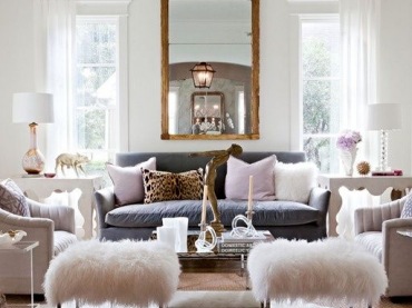 Poduszki, dywany czy puszyste siedziska wprowadzają do salonu wiele przytulności. Na komodach przy oknach ustawiono dwie lampy...