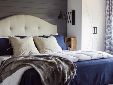 Żyrandol w sypialni i drewniane belki to bardzo odważny duet. Do tego eleganckie łóżko z bezowym zagłówkiem i poduchami...