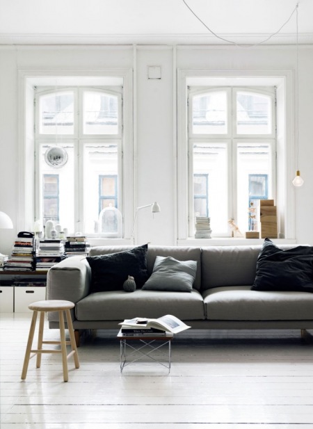 Jasnoszara sofa w nowoczesnym stylu i żarówka na kablu w skandynawskim salonie