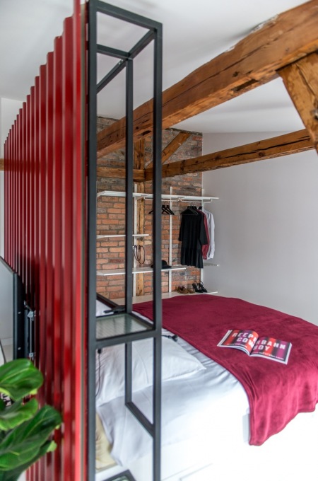 Aranżacja sypialni ze ścianą z cegieł i czerwonymi dodatkami