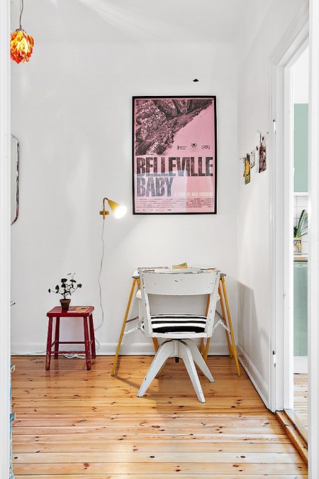 Mały  kącik biurowy z rózowym plakatem,malym stoliek i   białym krzeslem vinatge