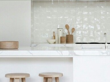 Białe nowoczesne szafki kuchenne,drewniane taborety,biała glazurowana płytka na ścianie i marmurowe blaty w minimalistycznej kuchni (26596)