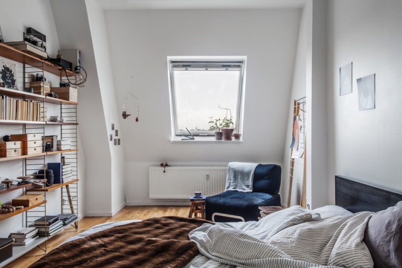 Skandynawska sypialnia z ażurowymi pólkami i granatowym fotelem