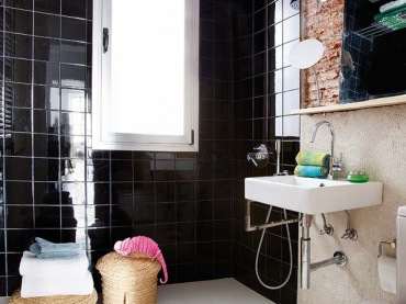 Połączenie czerwonej cegły i czarnych płytek w łazience z dodatkami w kolorze naturalnej wikliny świetnie podkreśla...