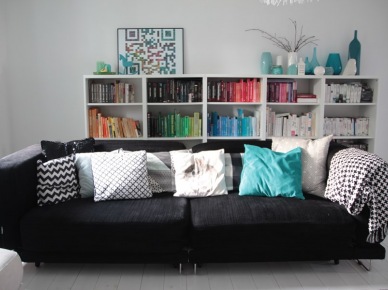 Czarna kanapa z dekoracyjnymi poduszkami w nowoczesnym salonie (49715)