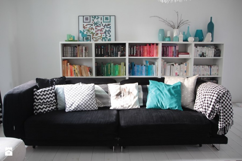 Czarna kanapa z dekoracyjnymi poduszkami w nowoczesnym salonie