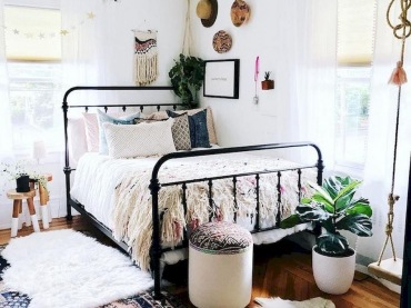Czarne łóżko zdecydowanie wyróżnia się w kolorowej sypialni. Wzorzysty dywan i asymetryczna galeria ścienna dodają...