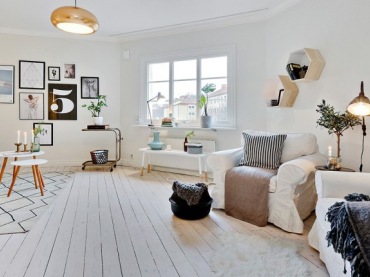 Skandynawskie palakty i grafiki na ścianie w salonie z białymi fotelami i okragłymi stolikami do kawy (27697)