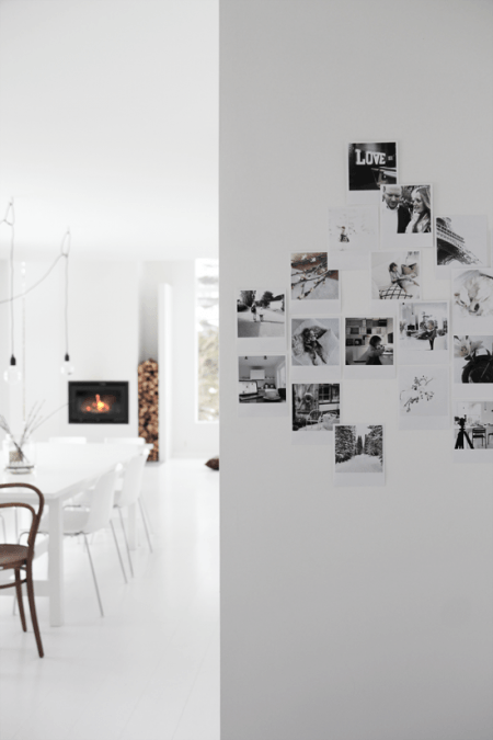 Biały salon z kominkiem i galeria rodzinnych fotografi na ścianie