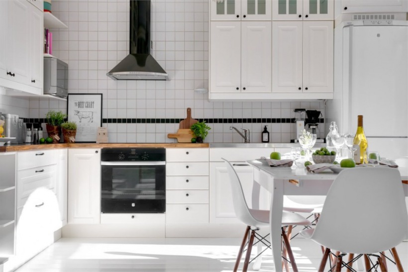 Czarny okap kuchenny,biała glazura na ścianie, biała podłoga i drewniane blaty w kuchni w stylu skandynawskim
