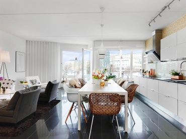 Szare nowoczesne leżanki , biały stół z białymi i miodowymi krzesłami i biała kuchnia w otwartym widoku mieszkania (24641)