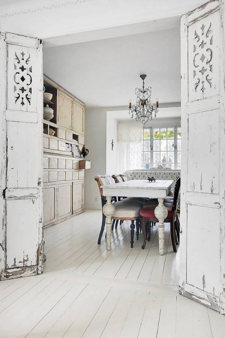 Prowansalskie drzwi vintage w białym wnętrzu jadalni z francuskimi meblami