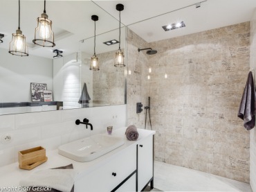Łazienka w stylu eklektycznym z oryginalnymi lampami i czarnymi dodatkami. Kafle z ciekawym motywem, którymi wyłożono fragment ściany pod prysznicem, wyraźnie wyodrębniają część...