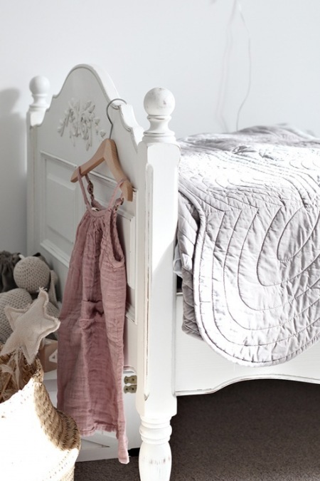 Białe łóżeczko z rzeźbioną ramą w aranżacji