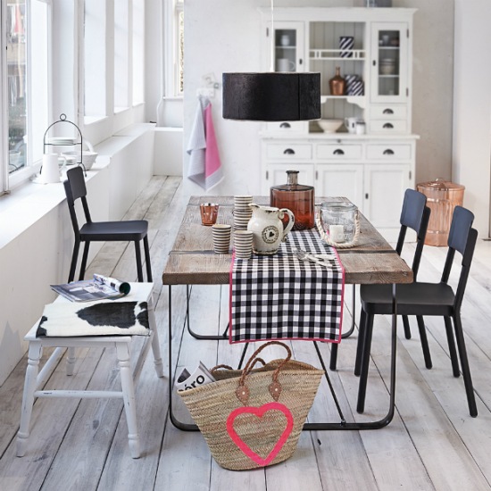 Biały kredens skandynawski,bielone deski ,metalowy stół z drewnianym surowym blatem i czarne krzesła z lampą nad stołem