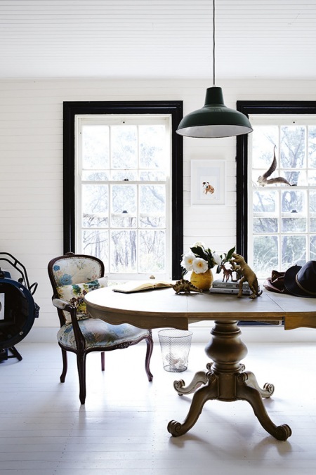 Industrialna lampa pendant,okrągły stół na stylowej nodze z francuskimi krzesłami i,czarne ramy okienne w białej jadalni