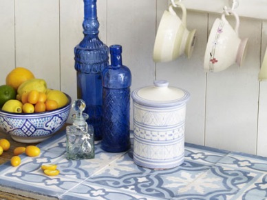 Śródziemnomorskie płytki w aranżacji kuchni z niebieska komodą i butelkami w kolorze indygo (23937)