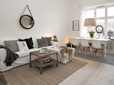 Biała kanapa z poduszkami i skórą w połączeniu z drewnianym stolikiem na kółkach (48846)