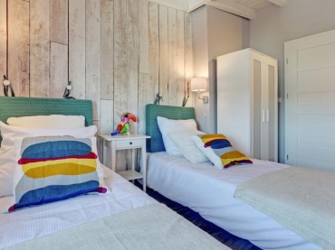 Nad łóżkami w sypialni zawieszono kinkiety, które podkreślają strukturę drewna. Ozdobna ściana świetnie wpisuje się w...