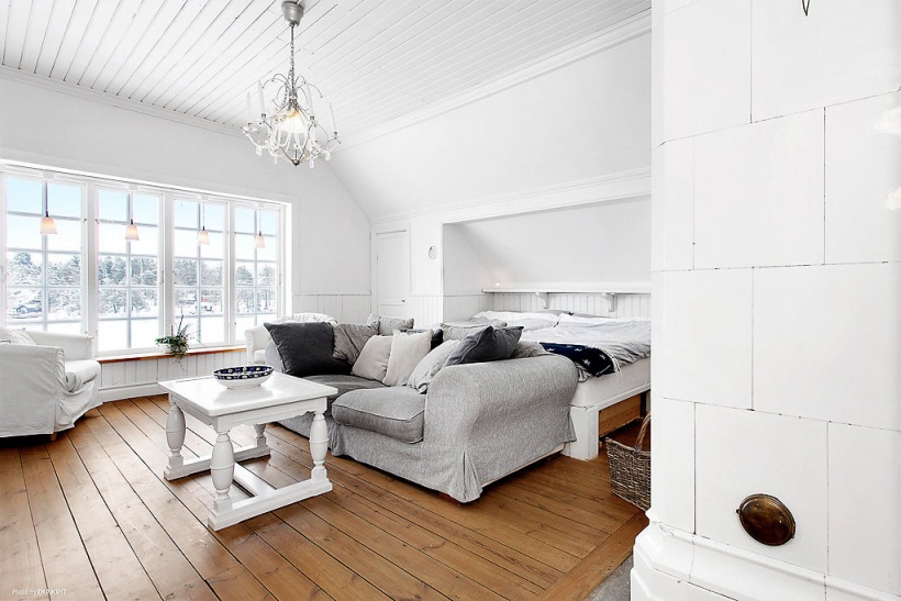 Drewniany biały stolik kawowy, szara sofa w dużej sypialni skandynawskiej