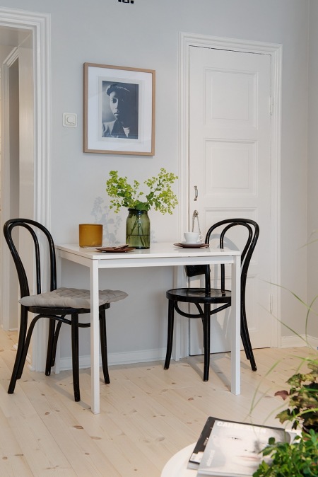 Mały biały stolik z czarnymi giętymi z drewna krzesłami  w małej jadalni